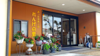 オレンジ色の壁面を持つ施設の玄関。花を飾った装飾的な入口で、ガラス扉が見える。